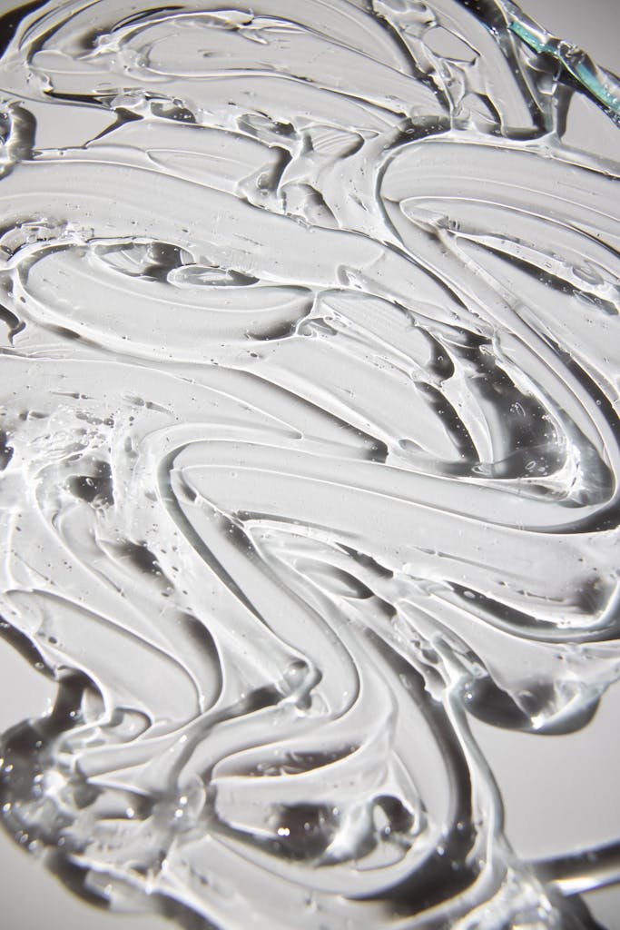 From above of backdrop representing shiny curved gel flows with irregular surface on gray background